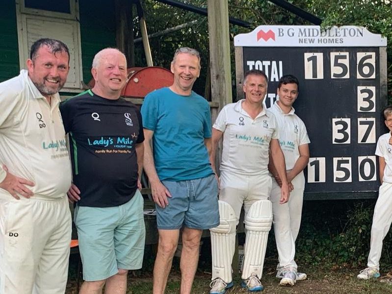 Daniel O'Connell (far left) in front of the scoreboard after reaching a century against Cullompton 4th XI<br>credit: Contributed
