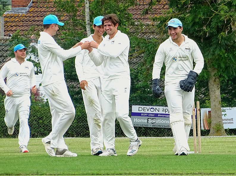 North Devon's Jack Popham is the centre of attention after taking a wicket in the win at Seaton