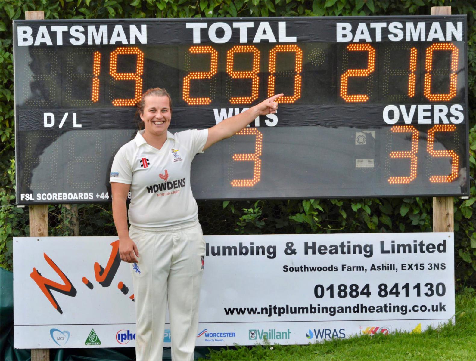 Ipplepen's Lydia Harris in front of the scoreboard showing her double hundred