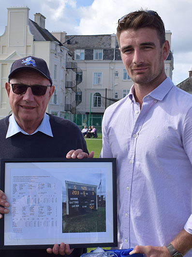 Mike Coxhead hands over a framed memento of the game against Dorset in which Josh Bess scored 203 and 70 and took six wickets and six catches.