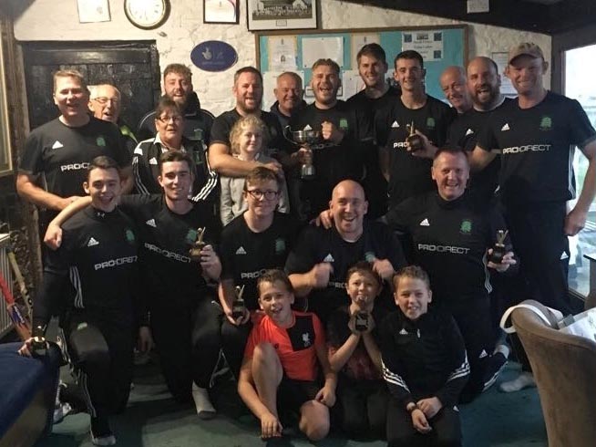 The victorious Barton team - and officials - celebrate in the long room at North Devon CC after beating Cullompton in the Ivor Dewdney's-sponsored Corinthian Cup final