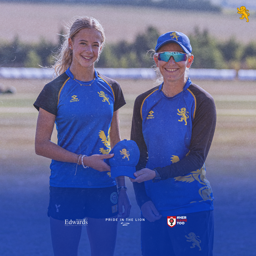 Maddie Russell is presented with her cap by captain Steph Hutchins before her Devon Women debut against Wiltshire in 2025.