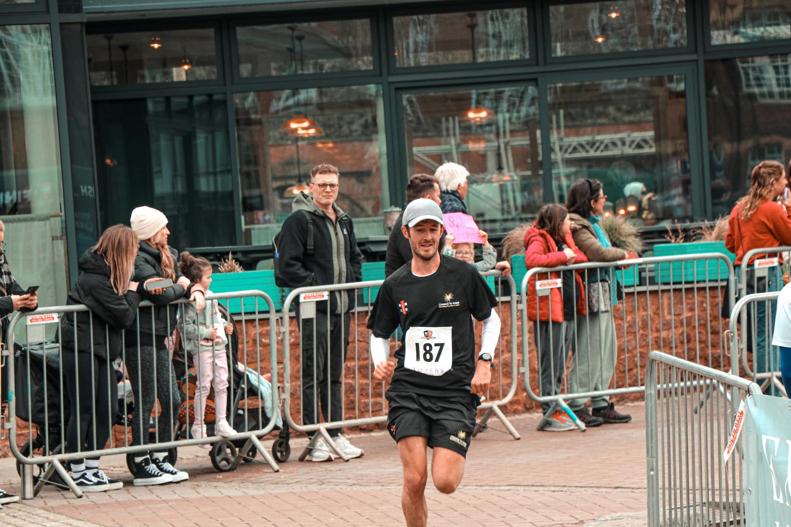 Alex crosses the finish line of the Exeter Half Marathon 2023. Credit: Exeter City Community Trust.